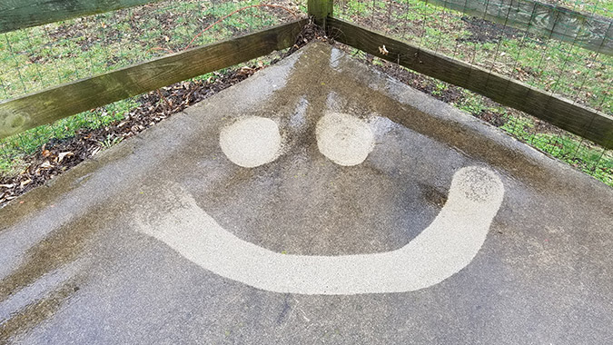 Dirty concrete with a smiley face pressure washed out of it