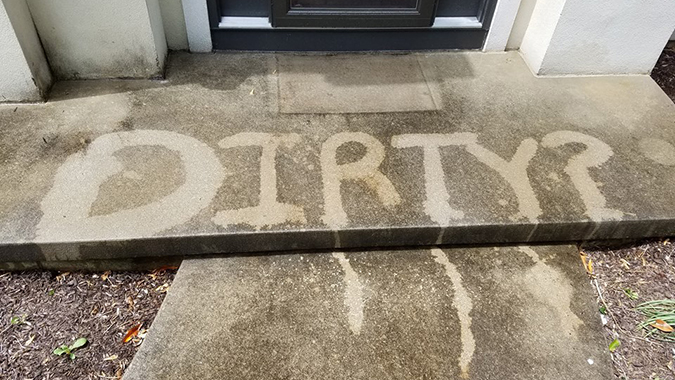 Dirty concrete with the word 'dirty' pressure washed out of it